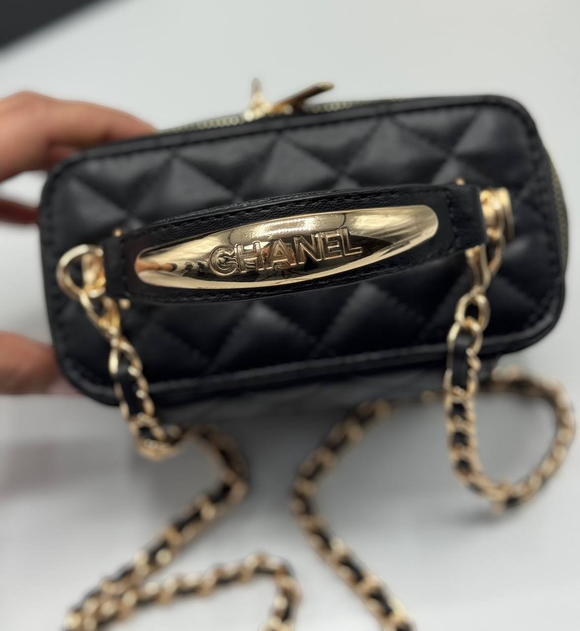 Chanel black quilted synthetic leather crossbody bag with gold chain strap and Chanel logo detail.