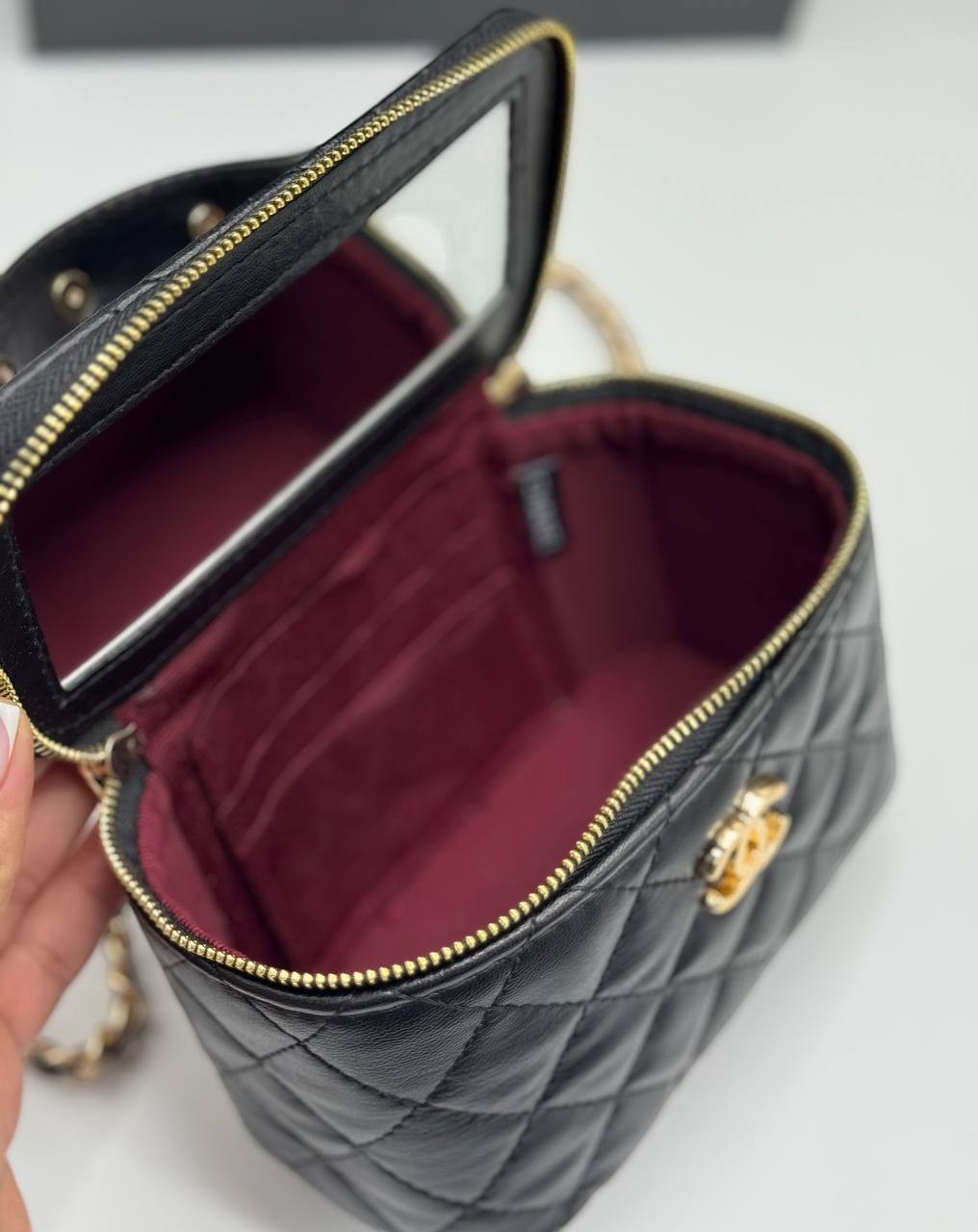 Chanel black quilted synthetic leather vanity crossbody bag with gold chain strap and internal mirror.
